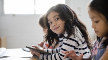 Portrait of smiling girl using digital tablet in classroom